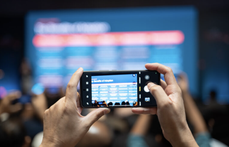 Attendee photographing a slide on their phone