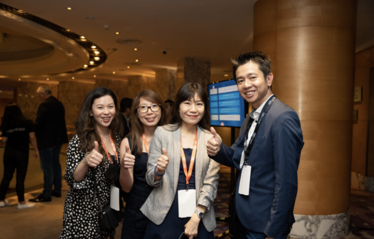 Attendees giving a thumbs up in the foyer