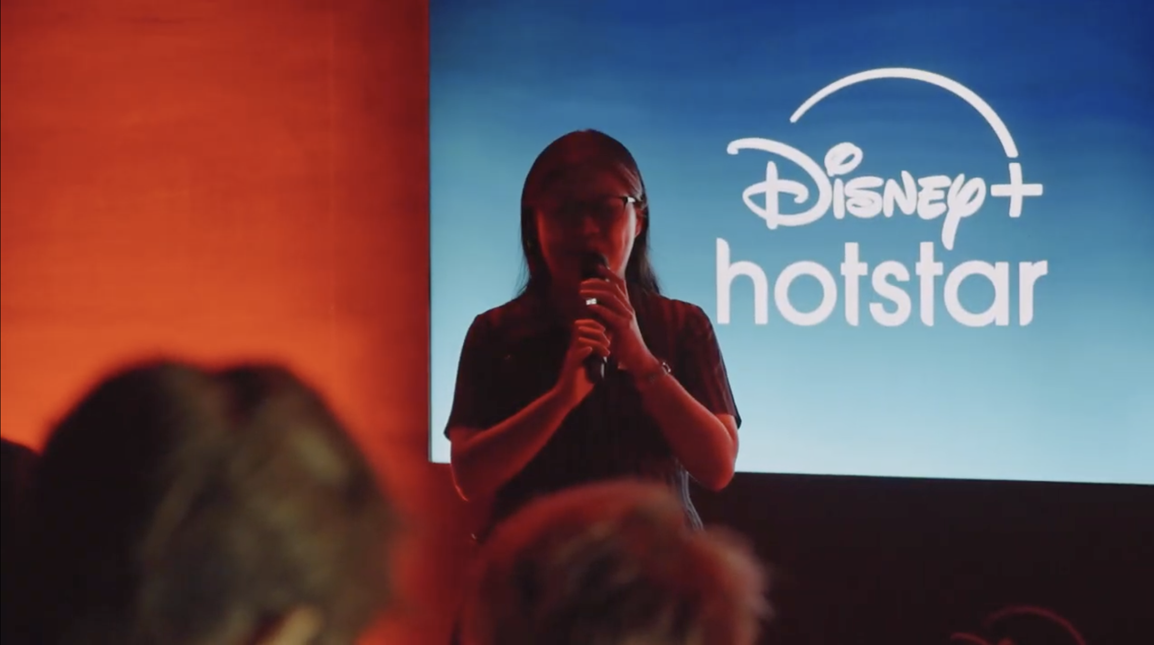 Host speaking in front of the Disney+ Hotstar screen