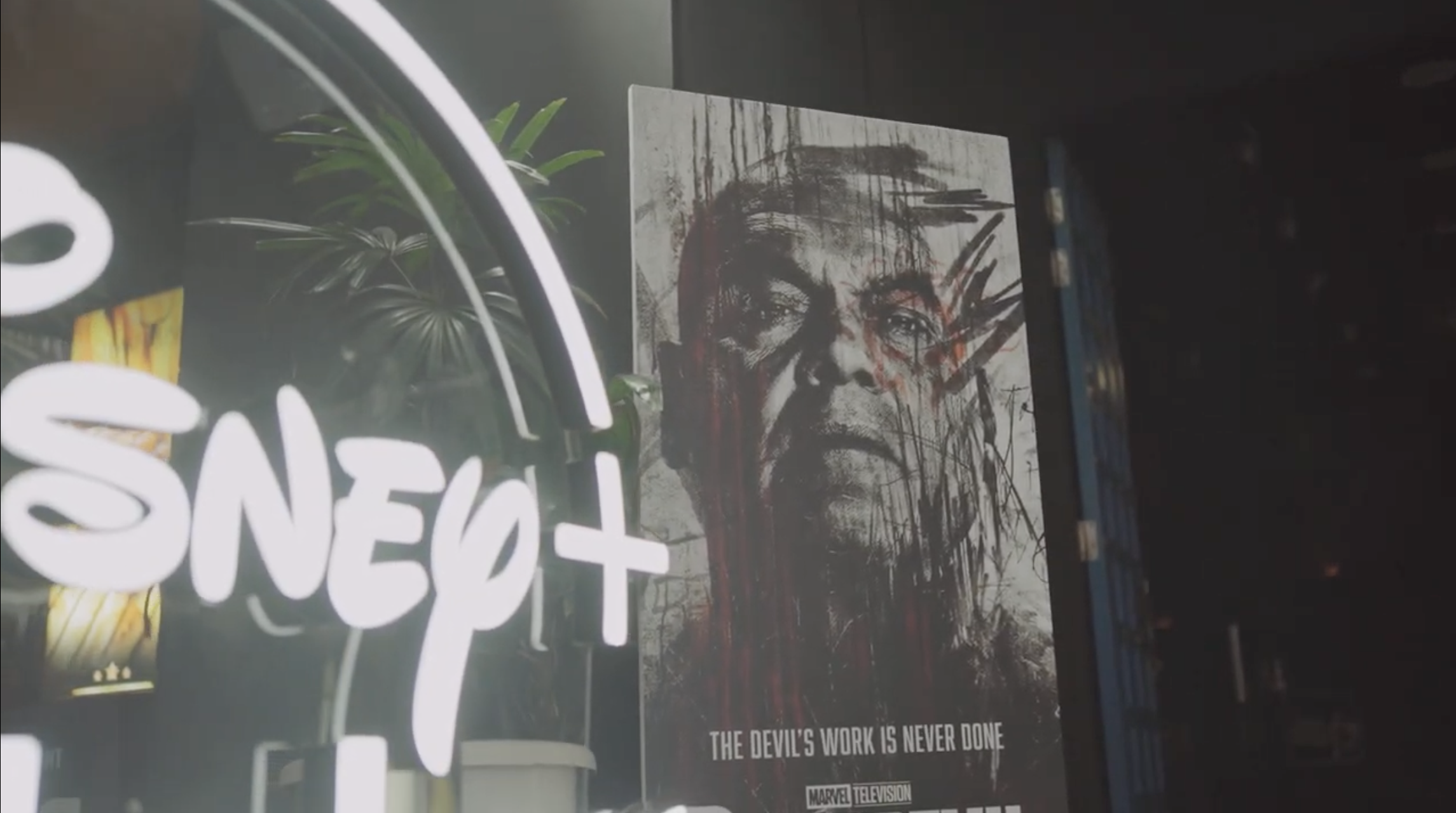 Disney+ neon sign beside a Daredevil: Born Again poster