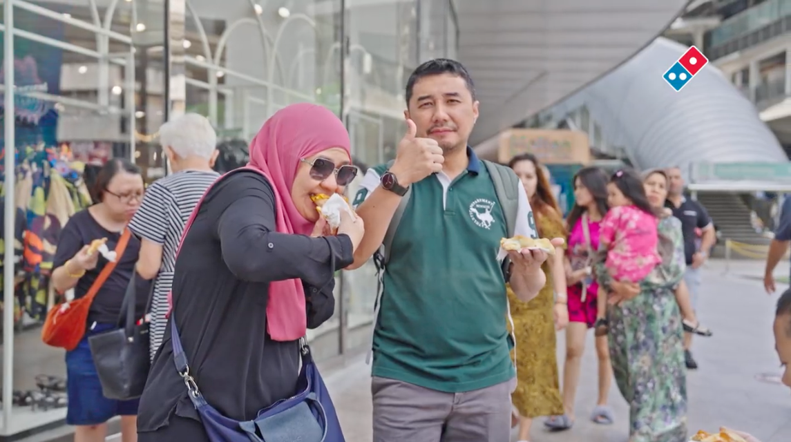 Happy customers tasting pizza on the street, thumbs up
