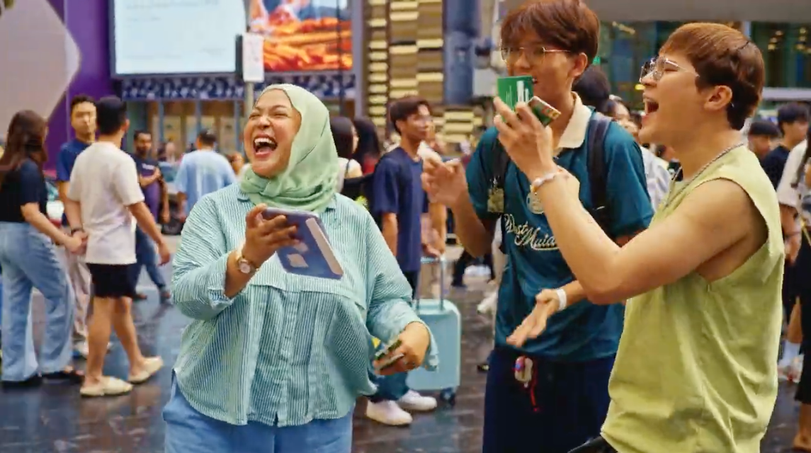 Shoppers laughing and cheering with Dine Out Deals cards on Bukit Bintang