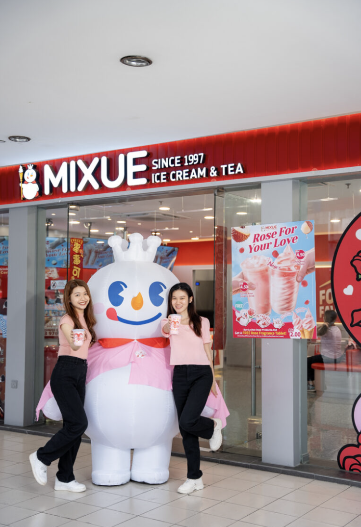 Two girls with the Snow King mascot outside a MIXUE store
